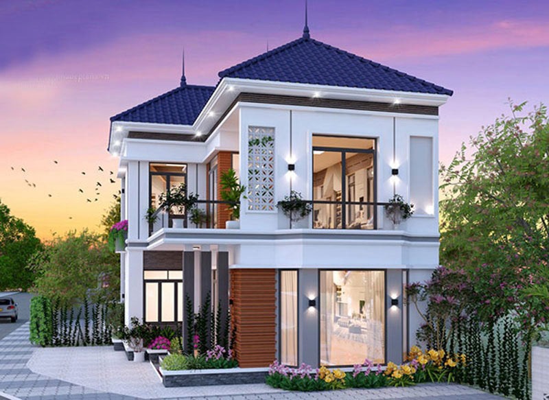 Nhà hai tầng hiện đại với mái ngói xanh và sân vườn xanh mát, dưới ánh hoàng hôn ấm áp.