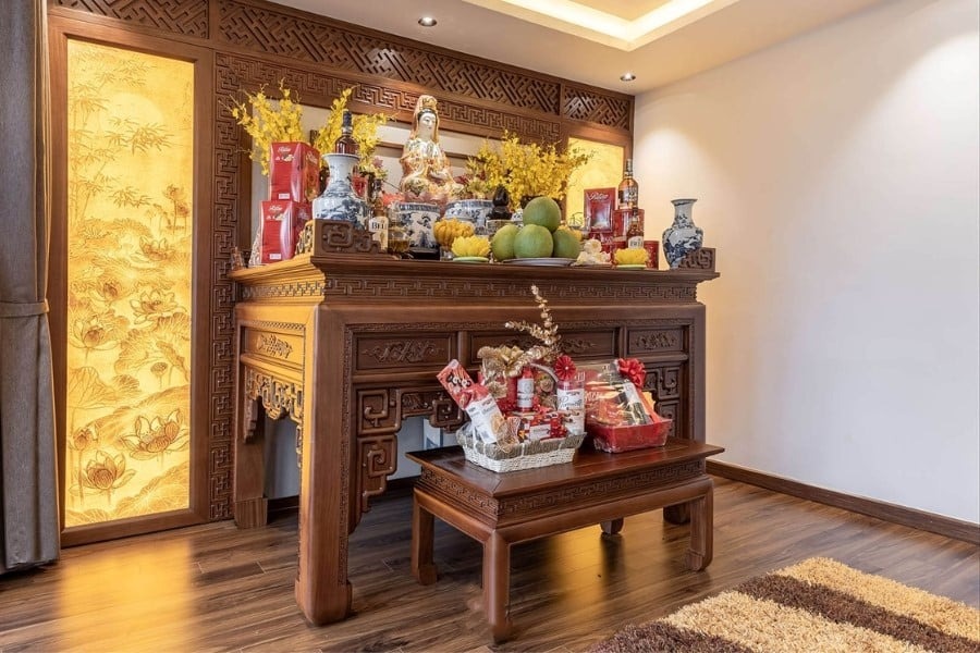 Bàn thờ gia tiên với tượng Phật Bà, đồ cúng và hoa vàng, mang ý nghĩa tôn kính trong không gian truyền thống.