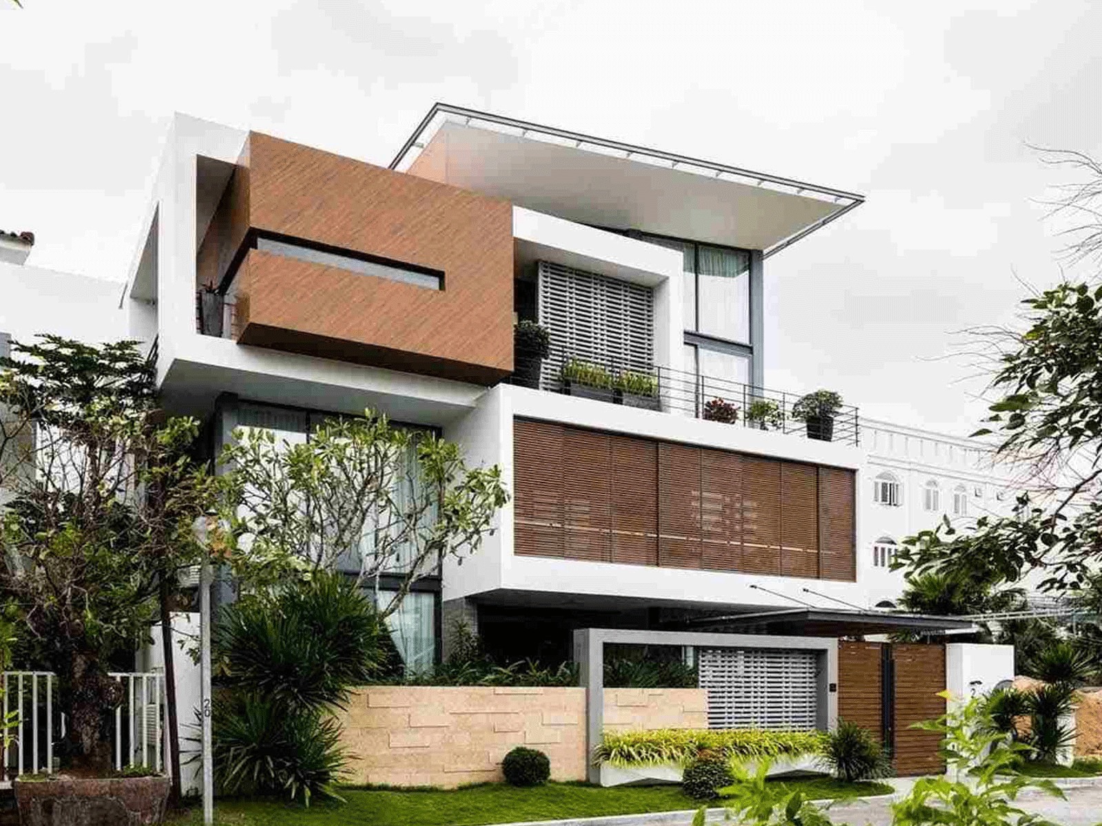 Nhà hiện đại sang trọng với thiết kế kiến trúc độc đáo, cửa sổ lớn và cây xanh xung quanh.