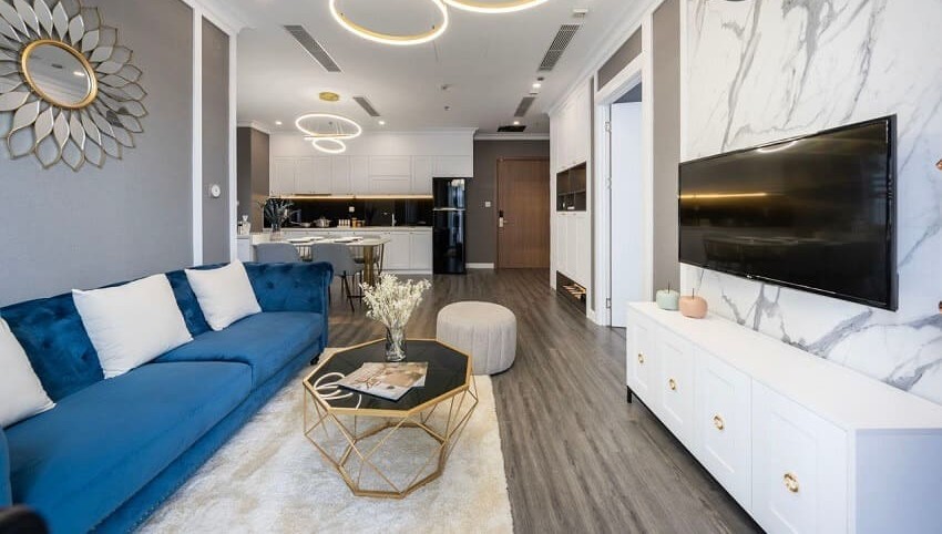 Phòng khách chung cư hiện đại với sofa màu xanh, bàn trà vàng và tivi treo trên tường, không gian nội thất trang nhã.