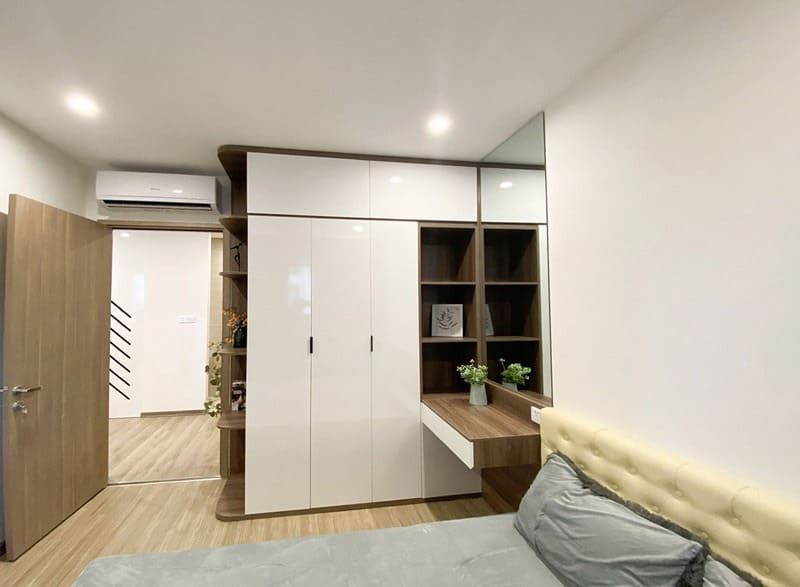 Phòng ngủ hiện đại với tủ âm tường trắng và bàn làm việc, trang trí cây xanh nhỏ gọn.