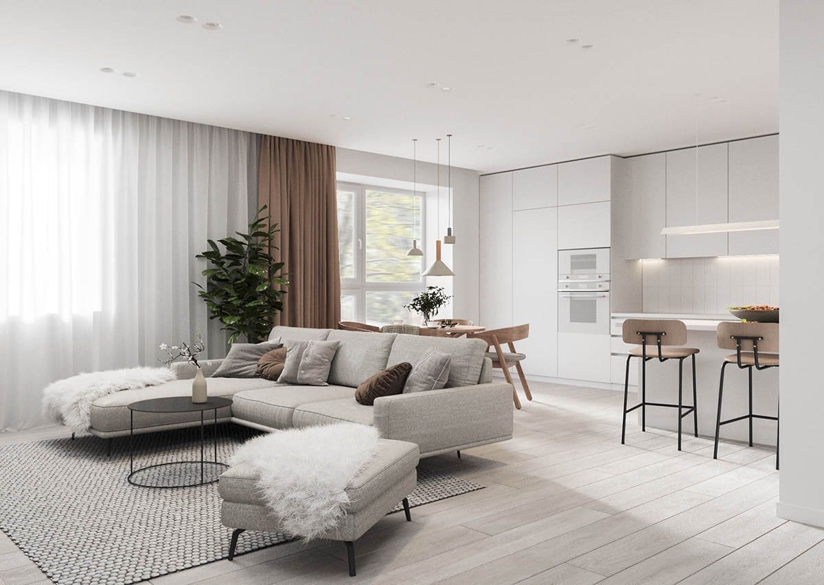 Phòng khách hiện đại với sofa màu xám, bàn tròn, cây xanh và bếp mở tông trắng, ánh sáng tự nhiên.