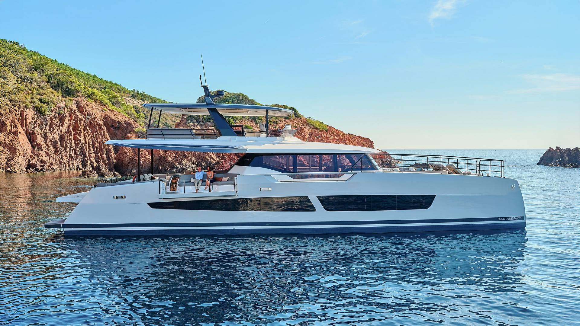 Du thuyền sang trọng màu trắng trên biển xanh, gần bờ đá, bầu trời trong lành.