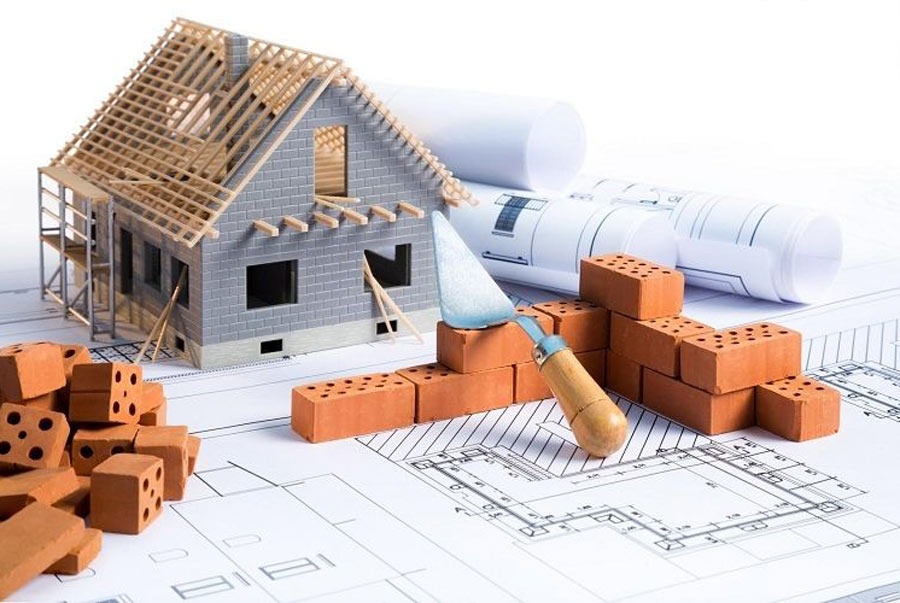 Mô hình nhà trên bản vẽ kiến trúc với gạch đỏ và bay xây dựng.