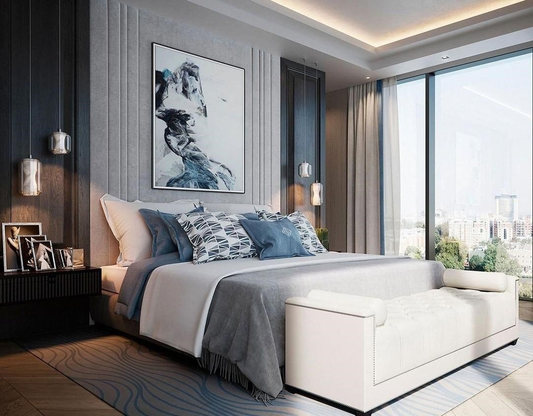 Phòng ngủ hiện đại với giường lớn, tranh nghệ thuật và cửa sổ kính lớn nhìn ra thành phố.