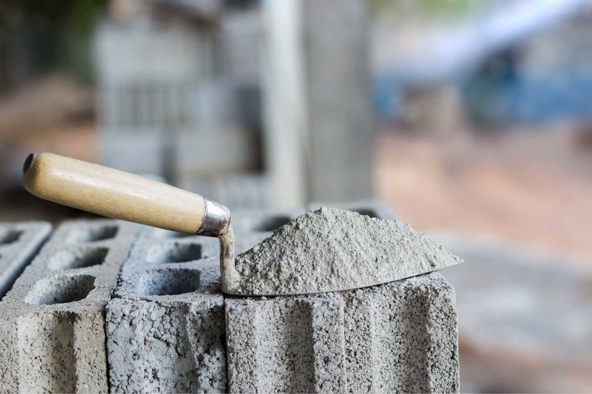 Bay xây dựng và vữa trên gạch xi măng, biểu tượng của công việc xây dựng.