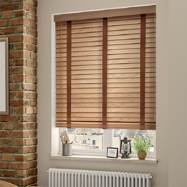 Mành gỗ nâu trên cửa sổ kính, phòng có tường gạch, trang trí cây xanh, đèn lồng, khung tranh.