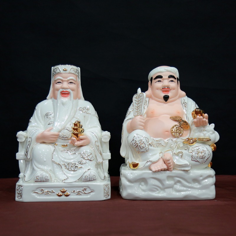 Tượng Thần Tài và Thổ Địa màu trắng ngồi trên bệ, mang ý nghĩa may mắn và thịnh vượng.