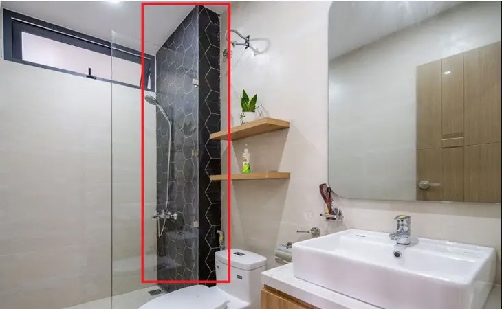 Phòng tắm hiện đại với vòi sen, bồn rửa và gương lớn, nền gạch đen tạo điểm nhấn sang trọng.
