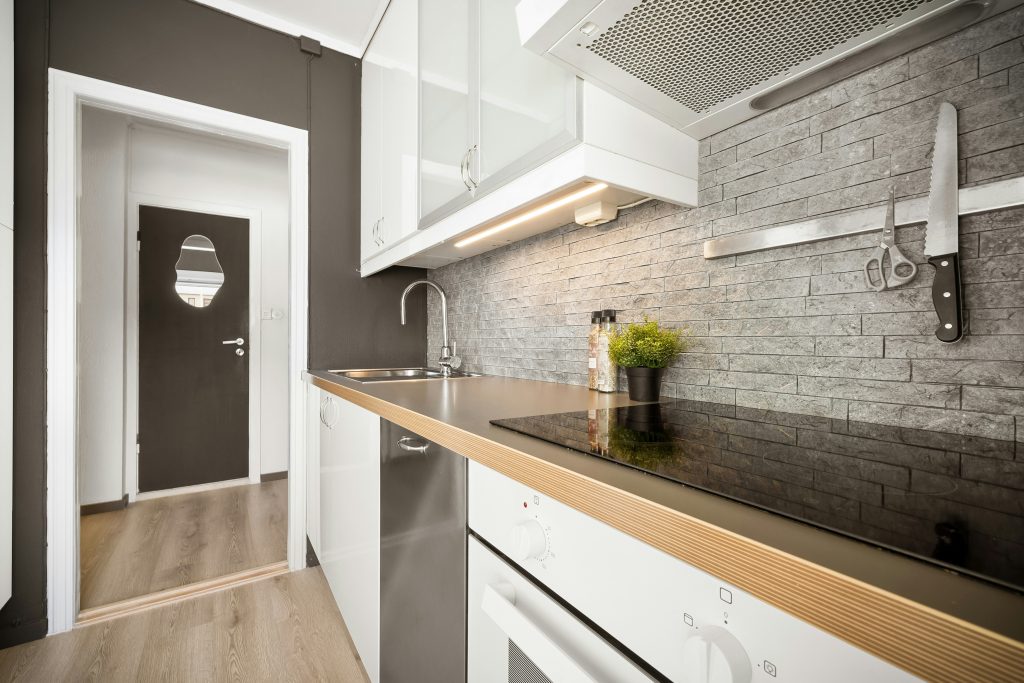 Nhà bếp hiện đại với mặt bếp đen bóng, tường gạch xám và cửa ra vào độc đáo.