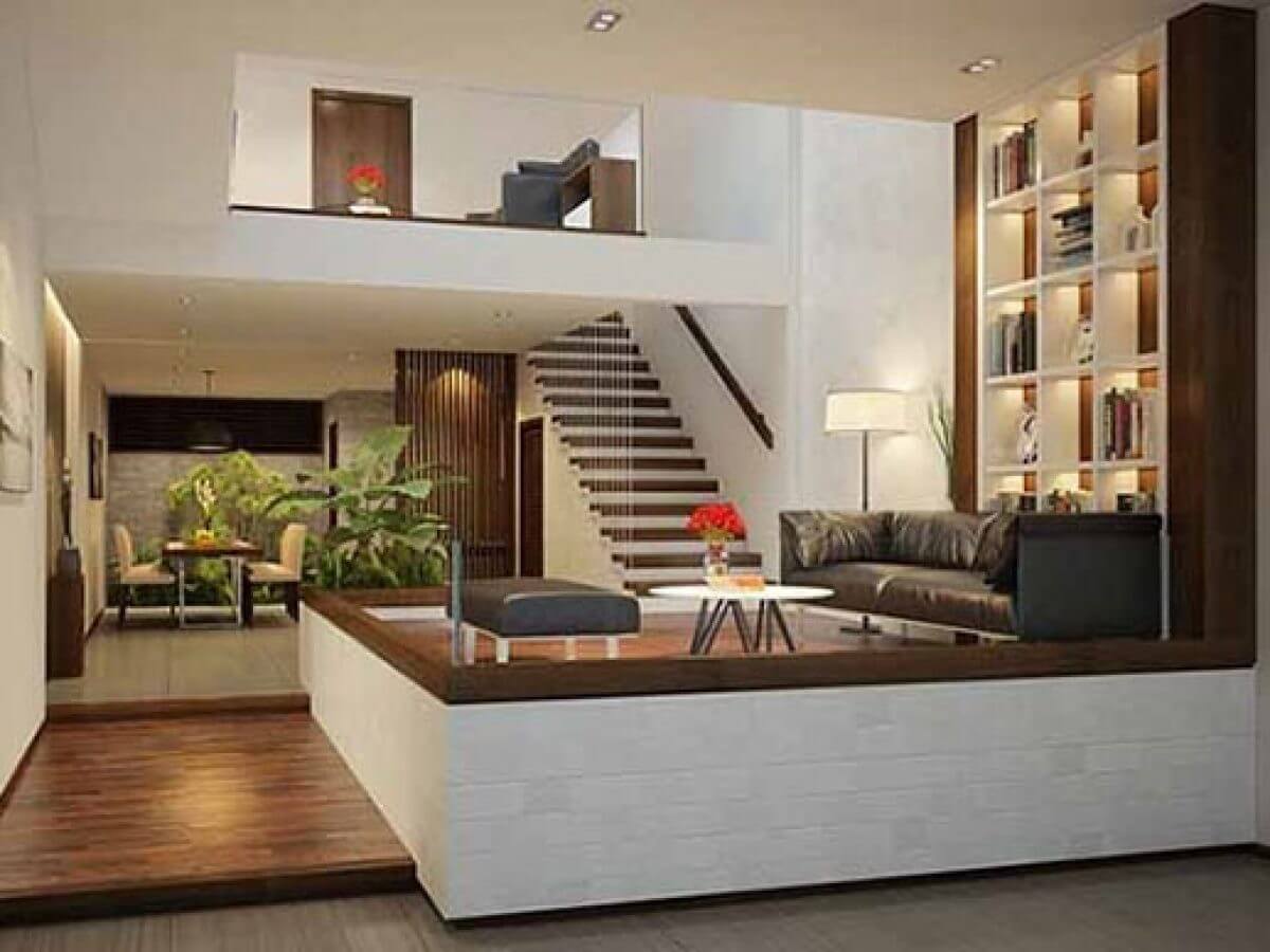 Phòng khách hiện đại với sofa da, kệ sách lớn và bàn cafe, không gian bếp rộng rãi.