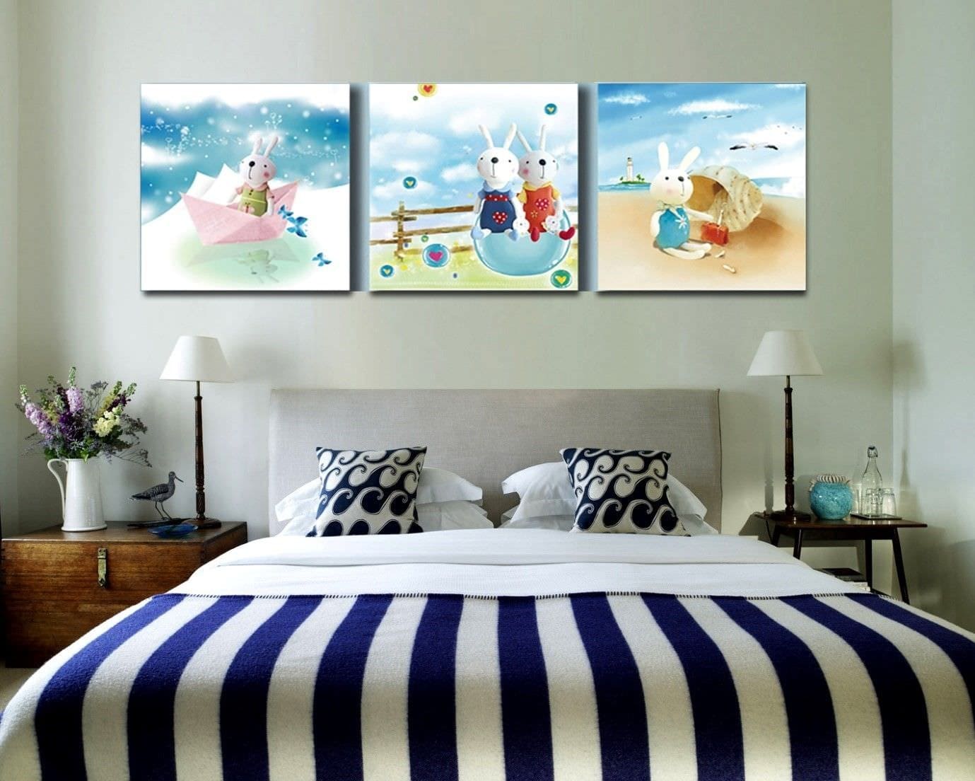 Tranh treo tường với hình ảnh thỏ hoạt hình trong phòng ngủ hiện đại, chăn sọc xanh trắng.