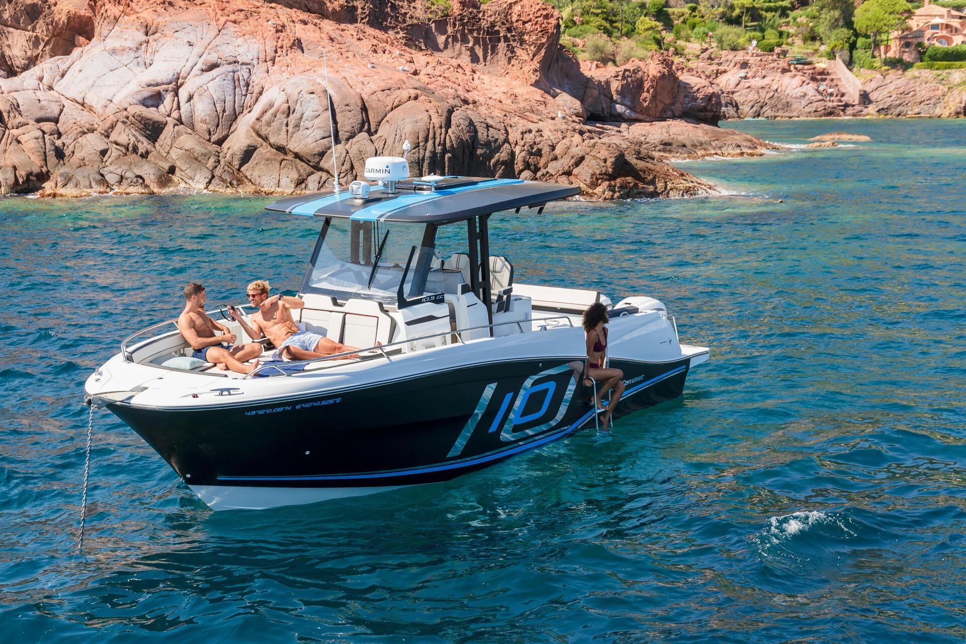 Thuyền máy trên biển xanh, hai người đàn ông thư giãn dưới ánh nắng, một người phụ nữ ngồi ở cuối thuyền.