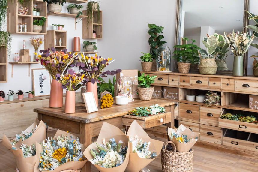 Cửa hàng hoa trang trí gỗ với các bó hoa rực rỡ và cây xanh tươi mát trên kệ.