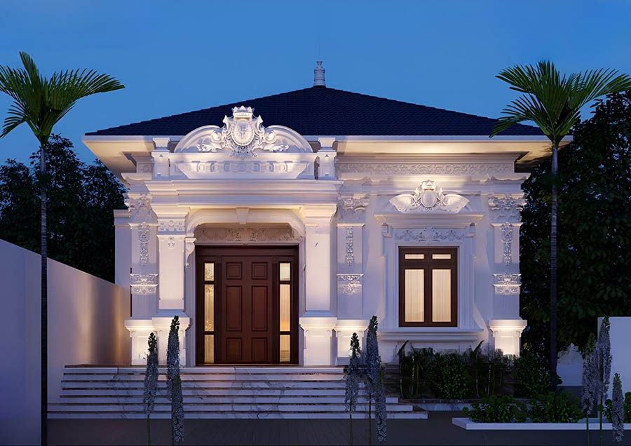 Nhà kiểu tân cổ điển với ánh sáng ban đêm, cửa gỗ lớn, trang trí hoa văn tinh tế và cây cọ hai bên.