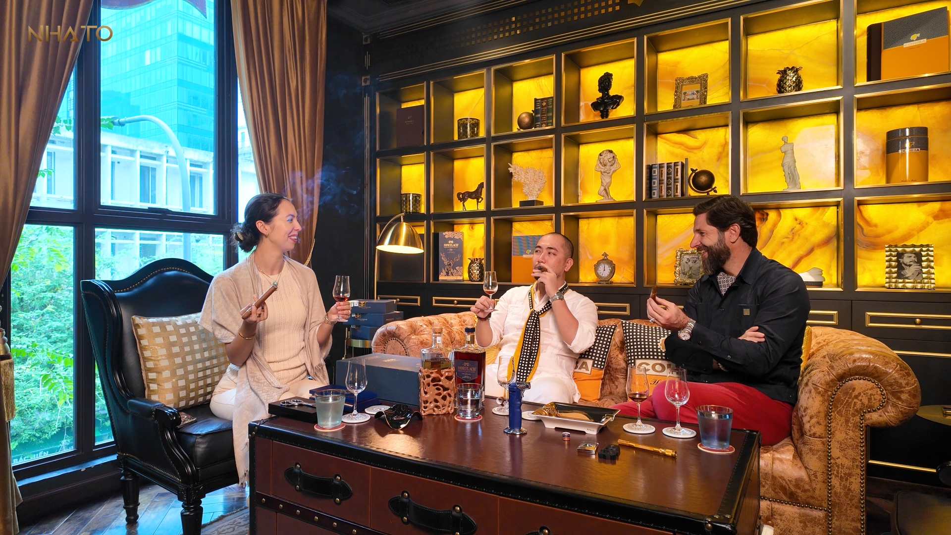 11-16 Ba người ngồi trong phòng khách sang trọng, thưởng thức xì gà và đồ uống.