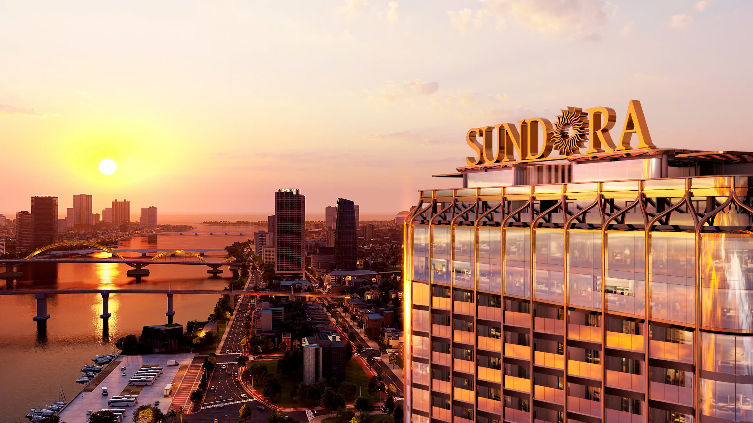 11-2-2 Tòa nhà Sundora rực rỡ trong ánh hoàng hôn, nhìn từ trên cao, với cảnh thành phố và dòng sông phía sau.