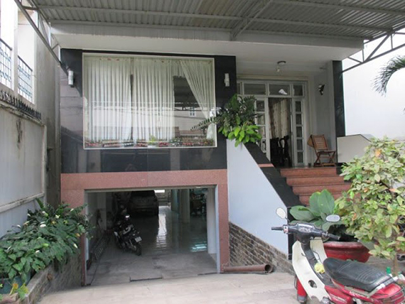 Ngôi nhà hiện đại với sân rộng phía trước, lối lên cầu thang và garage xe máy bên dưới.