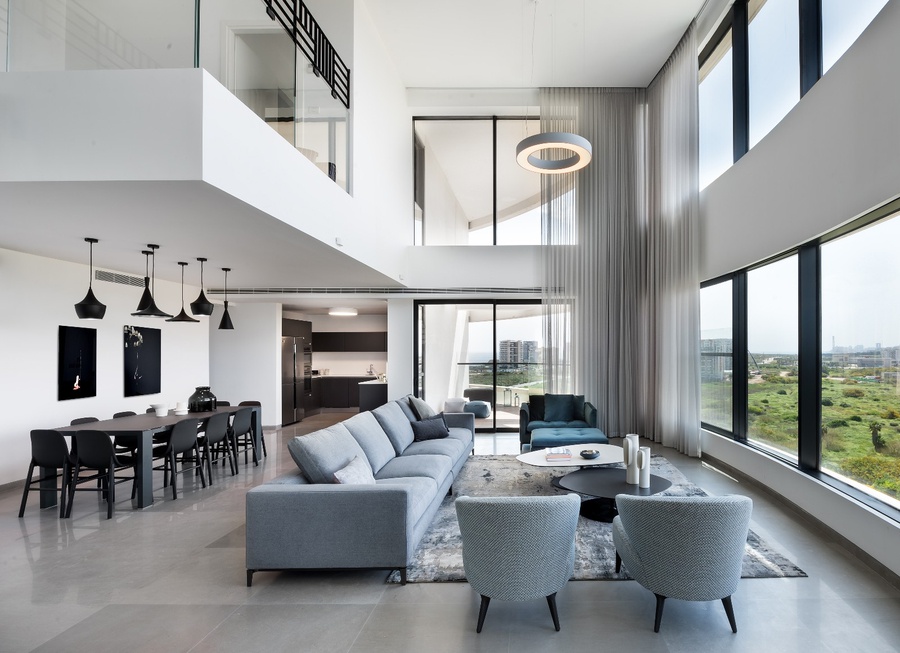Phòng khách hiện đại với nội thất sang trọng, cửa sổ lớn nhìn ra khung cảnh thành phố xanh tươi.