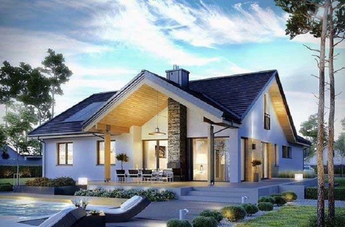 Ngôi nhà hiện đại với mái dốc, sân vườn rộng rãi và bể bơi nhỏ, trời xanh trong và cây xanh bao quanh.