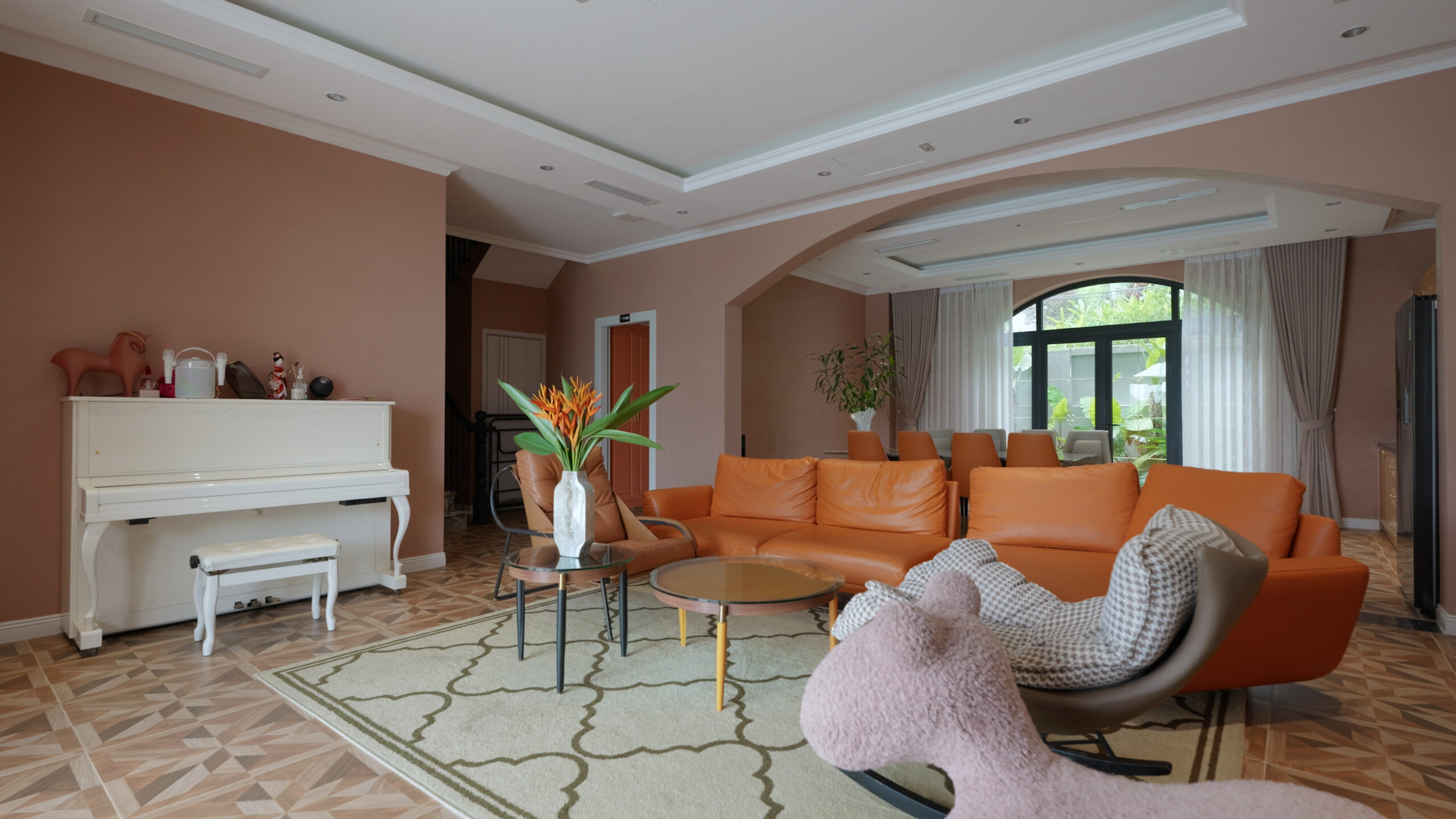 Phòng khách hiện đại với ghế sofa da cam, đàn piano trắng và cửa sổ lớn.