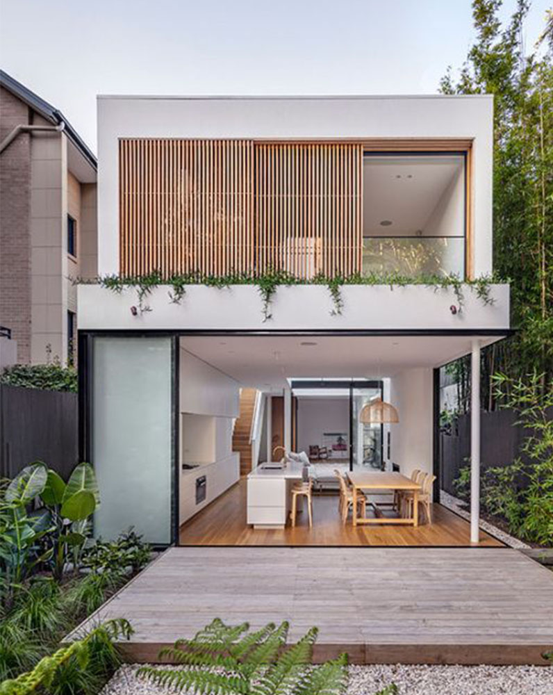 Nhà hiện đại hai tầng với thiết kế tối giản, cửa kính lớn và sân vườn xanh tươi phía trước.