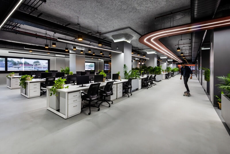 Văn phòng hiện đại với nội thất tối giản, nhiều cây xanh và người trượt ván.
