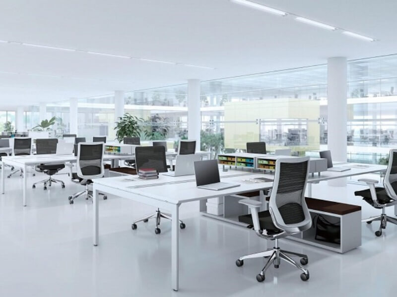 Văn phòng làm việc hiện đại với bàn trắng, ghế xoay và máy tính, không gian mở và ánh sáng tự nhiên.