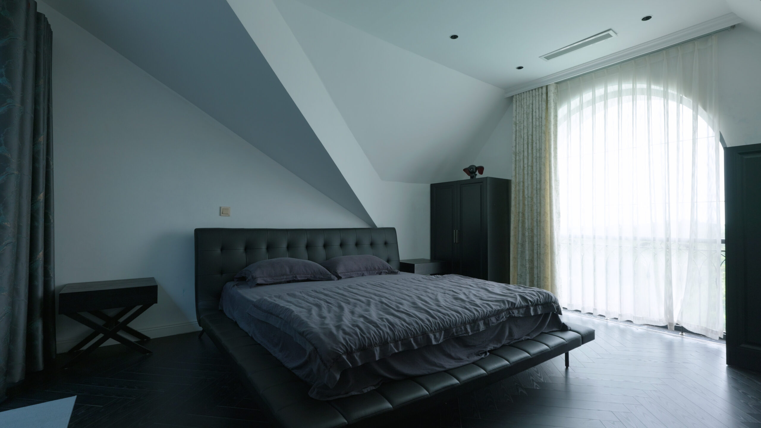 Phòng ngủ sang trọng với giường lớn màu đen, ánh sáng tự nhiên từ cửa sổ rộng có rèm trắng.