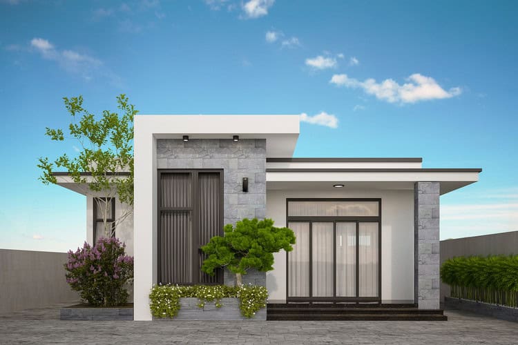 Ngôi nhà hiện đại có mái bằng, tường xám, cửa kính lớn, bao quanh cây xanh và bầu trời xanh trong.