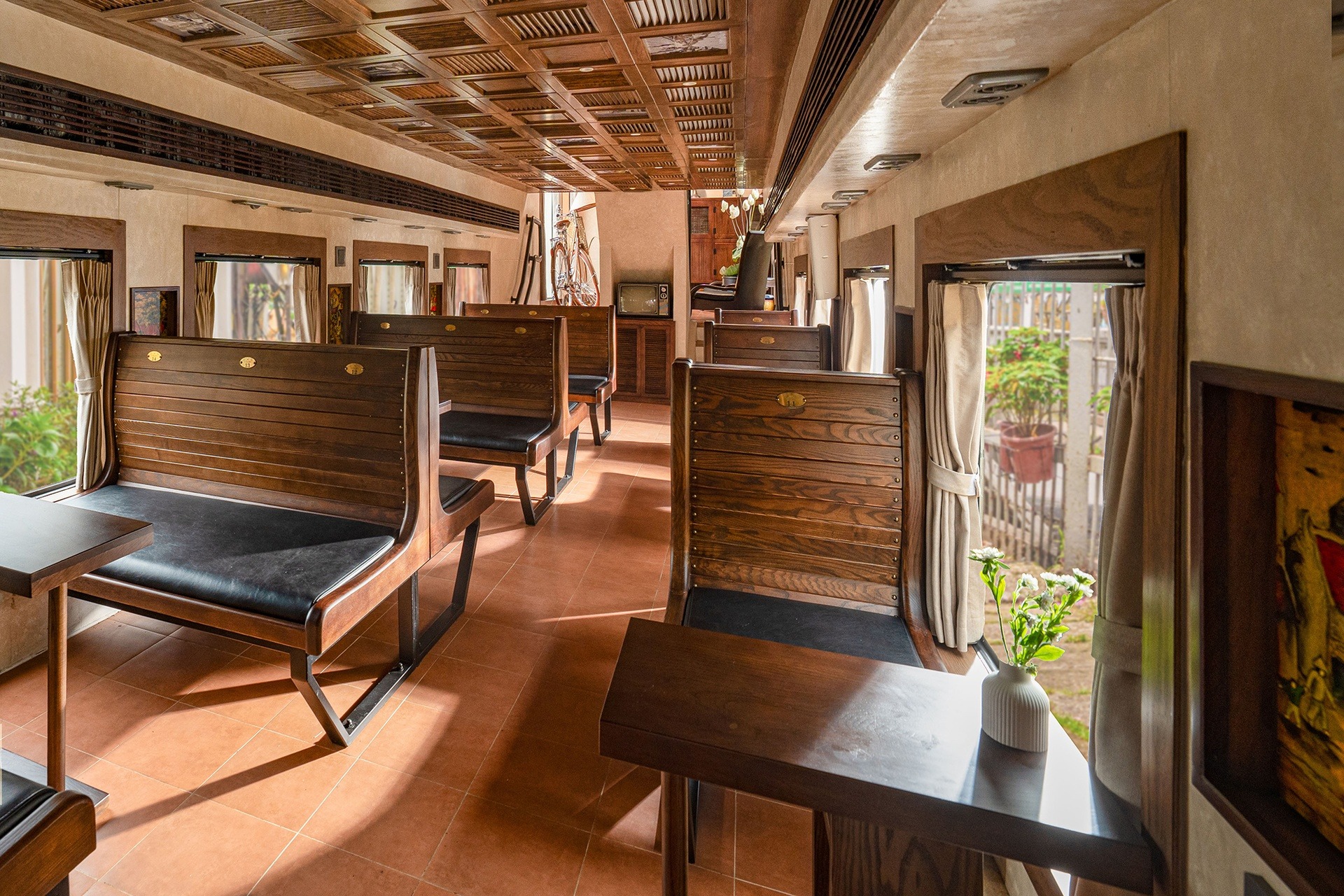 Nội thất quán cà phê theo phong cách toa tàu với ghế gỗ xưa và ánh sáng tự nhiên ấm áp.