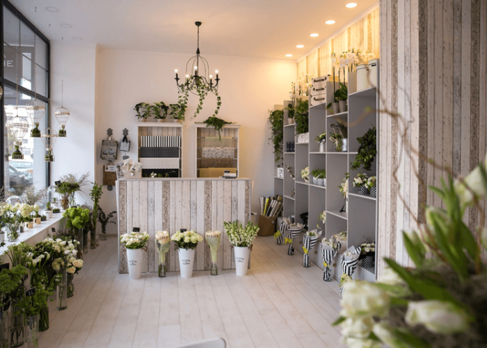 Cửa hàng hoa trang trí hiện đại, ánh sáng ấm áp, hoa tươi màu trắng chủ đạo, kệ hoa gọn gàng và đẹp mắt.