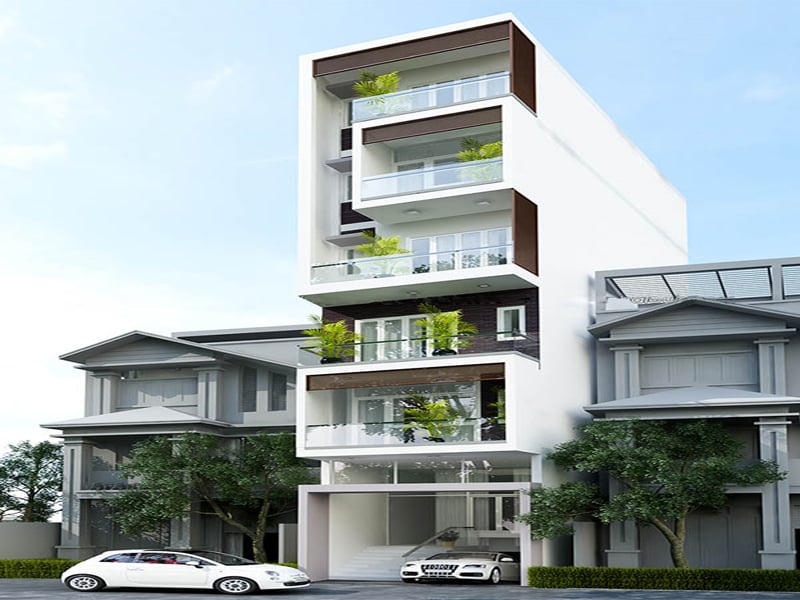 Tòa nhà hiện đại nhiều tầng với cây xanh, có hai xe ô tô đỗ phía trước, nằm giữa khu phố.