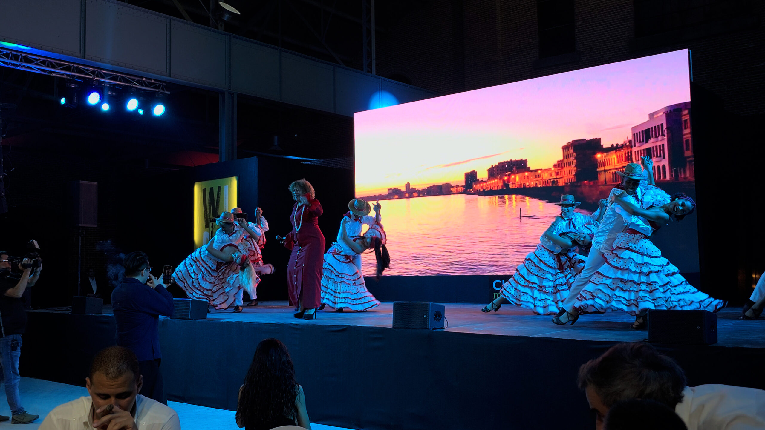 29-scaled-1 Nhóm vũ công biểu diễn trước màn hình LED hiển thị cảnh hoàng hôn trên biển tại một sự kiện trong nhà.