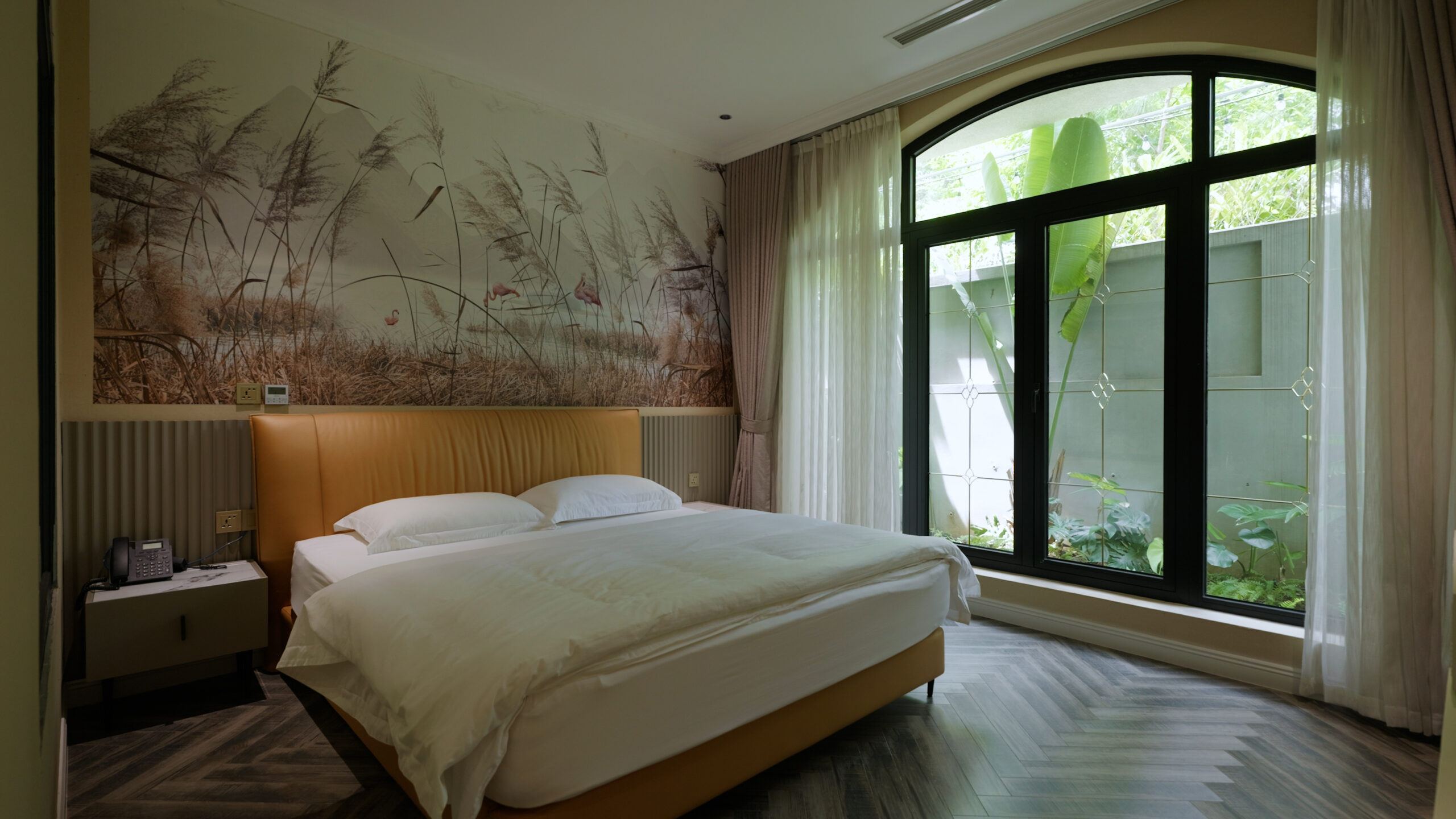 30-1-scaled-1 Phòng ngủ hiện đại với giường lớn, cửa sổ kính lớn nhìn ra vườn xanh mát, tường trang trí hình cỏ lau.