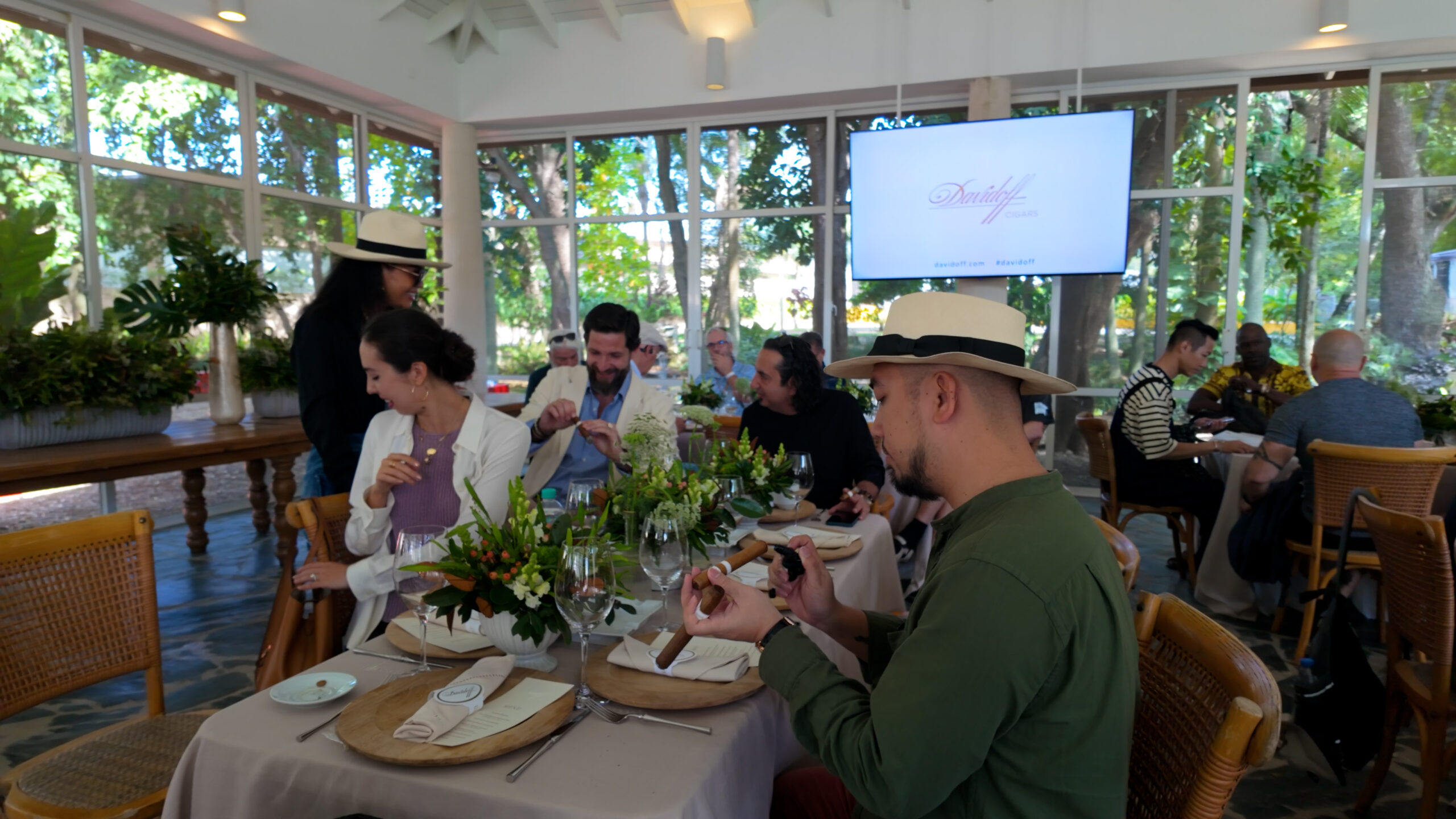 Nhóm người tham gia sự kiện trong không gian nhà hàng, trên bàn có hoa và thực đơn.