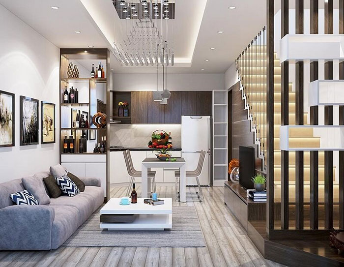 Phòng khách hiện đại với sofa xám, bàn kính và đèn chùm, trang trí sáng tạo và cầu thang gỗ.