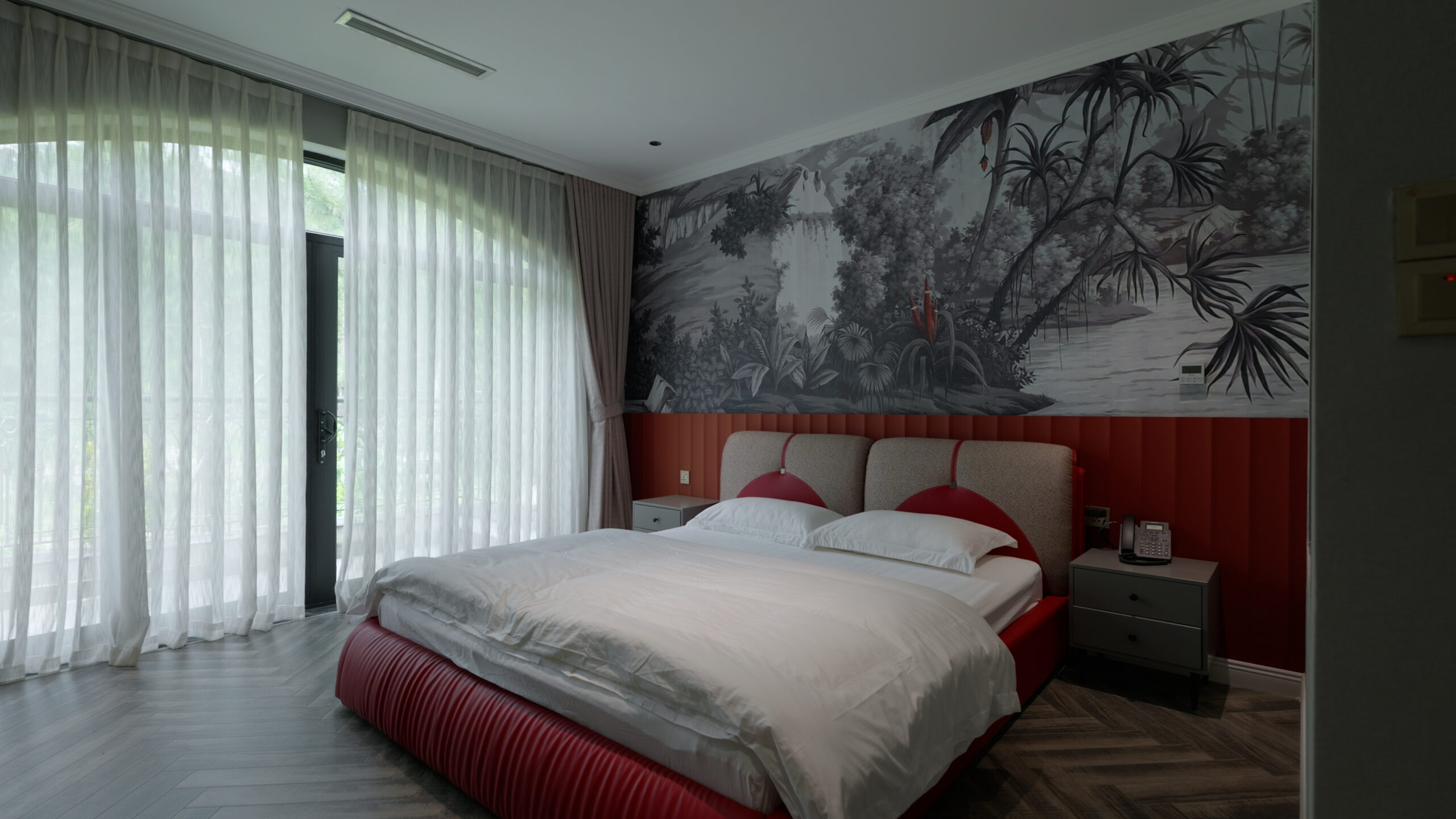 34-scaled-1 Phòng ngủ hiện đại với giường đôi, tường trang trí cây nhiệt đới và cửa sổ lớn.