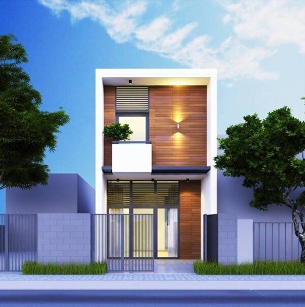 Nhà phố hiện đại hai tầng với mặt tiền gỗ, hàng rào sắt, cây xanh bên ngoài trời xanh.