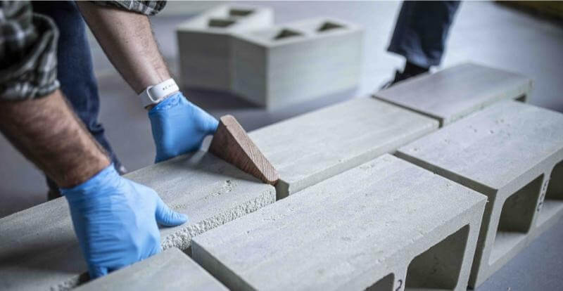 Người thợ xây dùng bay gỗ chỉnh các viên gạch bê tông trên công trường xây dựng.