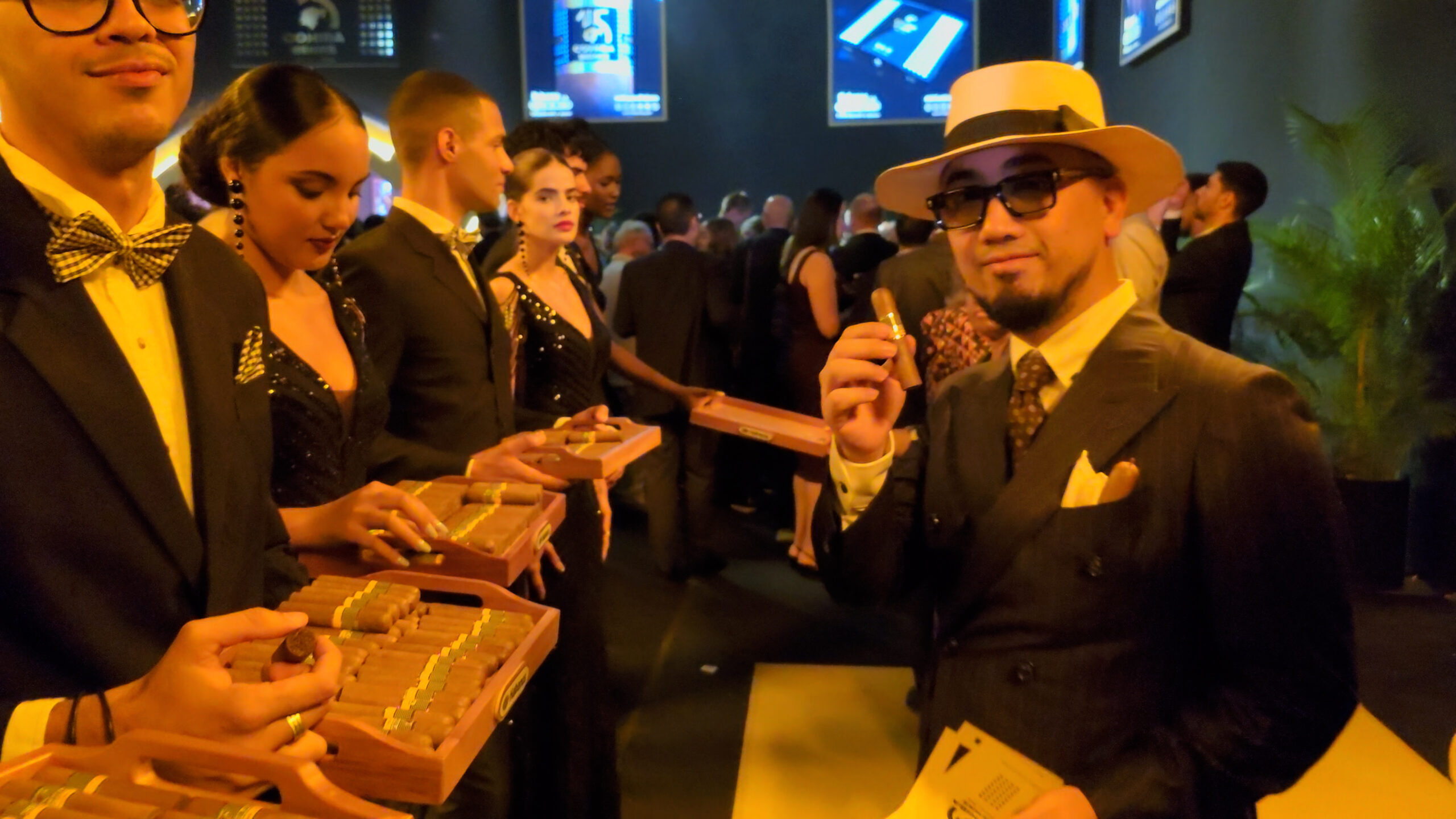 49-scaled-1 Người đàn ông sang trọng cầm điếu xì gà trong bữa tiệc tối lịch lãm với nhiều khách mời và phục vụ.