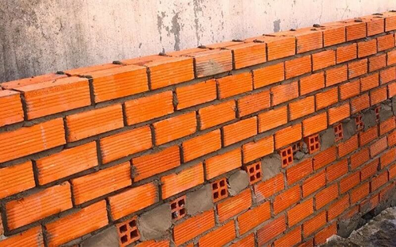 Bức tường gạch đỏ đang xây dựng với kết cấu đều đặn, thể hiện quy trình thi công xây dựng chuyên nghiệp.