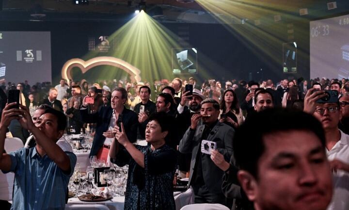 5-1-2 Mọi người cầm điện thoại ghi lại khoảnh khắc trong sự kiện sang trọng dưới ánh sáng sân khấu.