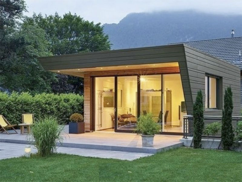 5-thiet-ke-nha-vuong-10x10-1-tang-doc-dao Nhà gỗ hiện đại với cửa kính lớn, sân vườn cắt tỉa gọn gàng và phong cảnh núi non phía sau.