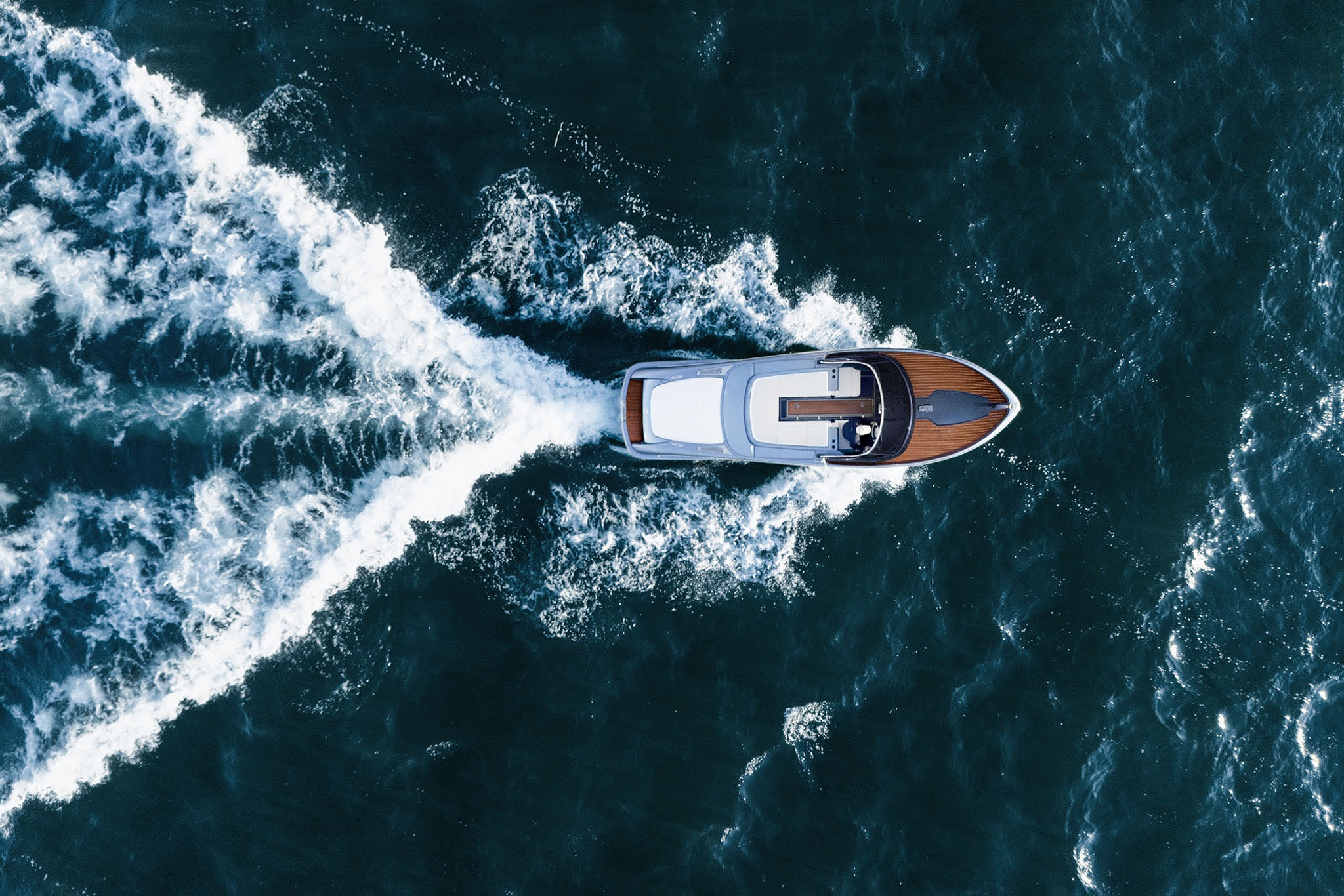 Du thuyền đang chạy trên biển xanh, tạo sóng trắng nổi bật từ góc nhìn trên cao.