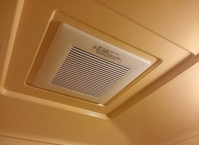 Quạt thông gió trần phòng tắm màu trắng trên nền trần màu be, thiết kế hiện đại, giúp thông thoáng không khí.