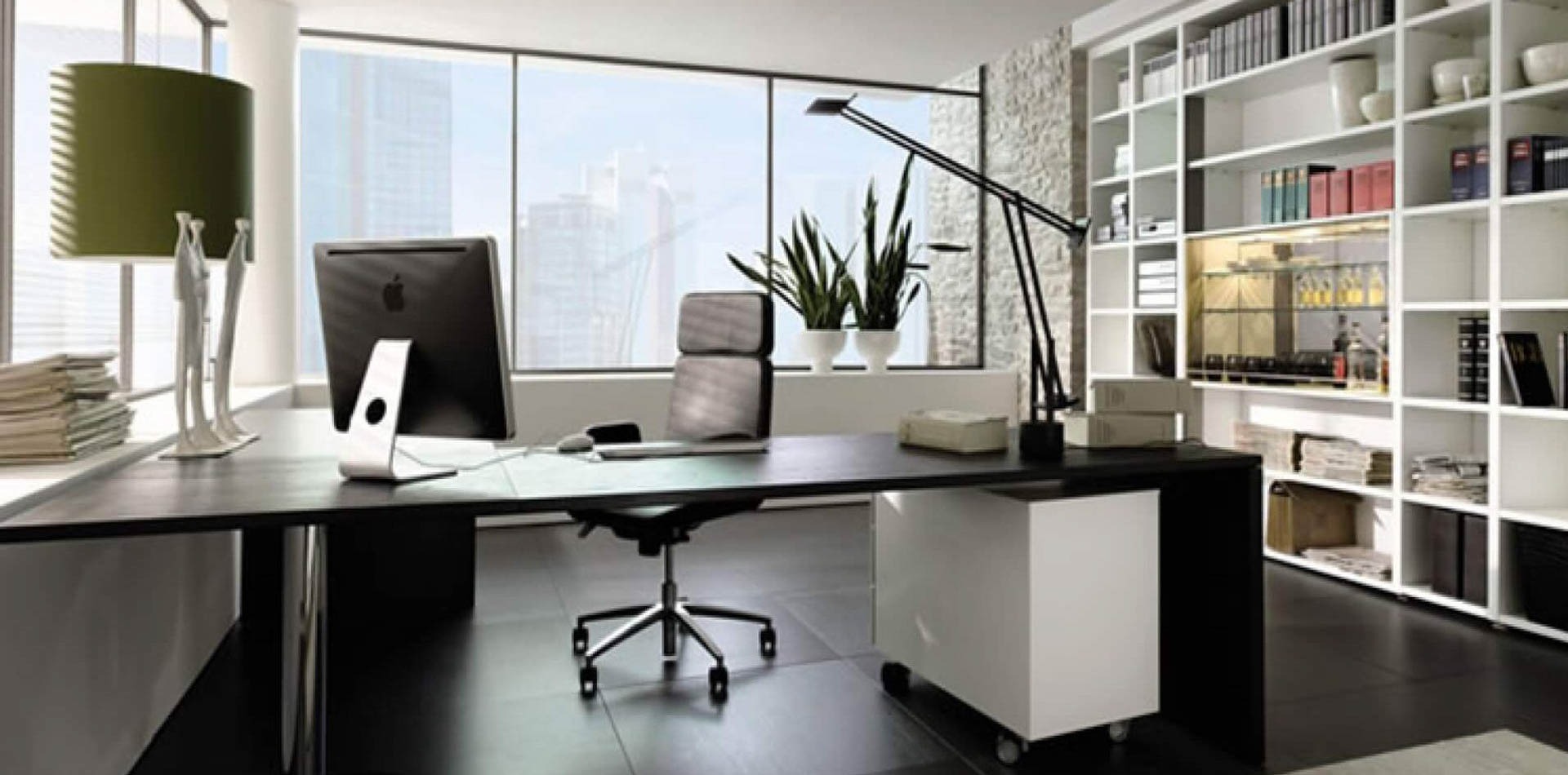 Văn phòng hiện đại với bàn làm việc, máy tính và kệ sách trang trí. Không gian sáng sủa, gọn gàng và chuyên nghiệp.