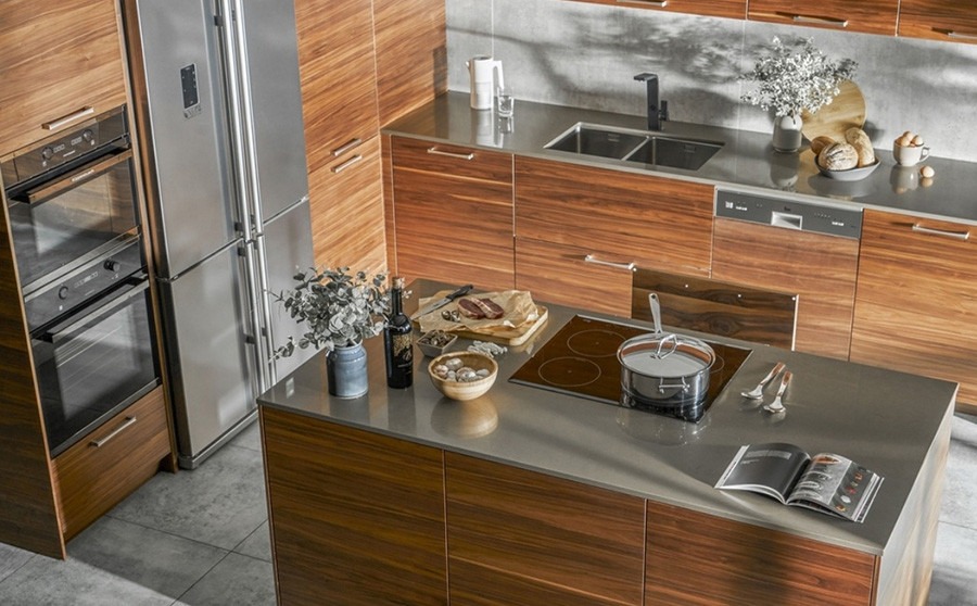 Nhà bếp hiện đại với tủ gỗ, mặt đá, bếp từ và các thiết bị gia dụng hiện đại.