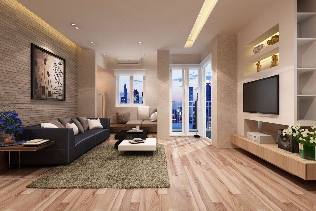 Phòng khách hiện đại với sofa đen, tranh treo tường, cửa sổ kính và tivi, sàn gỗ ấm cúng.