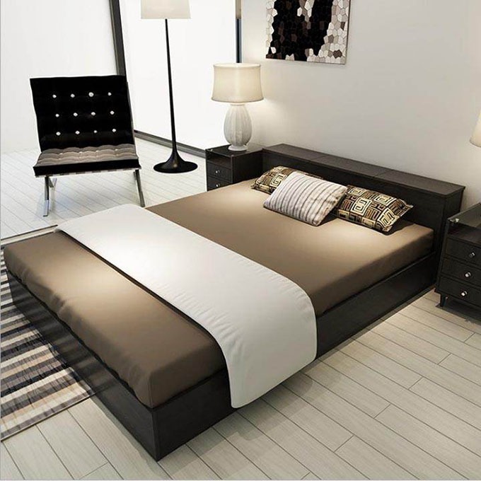 Phòng ngủ hiện đại với giường đôi, đèn ngủ và ghế bành, tông màu nâu nhạt tạo cảm giác ấm cúng.